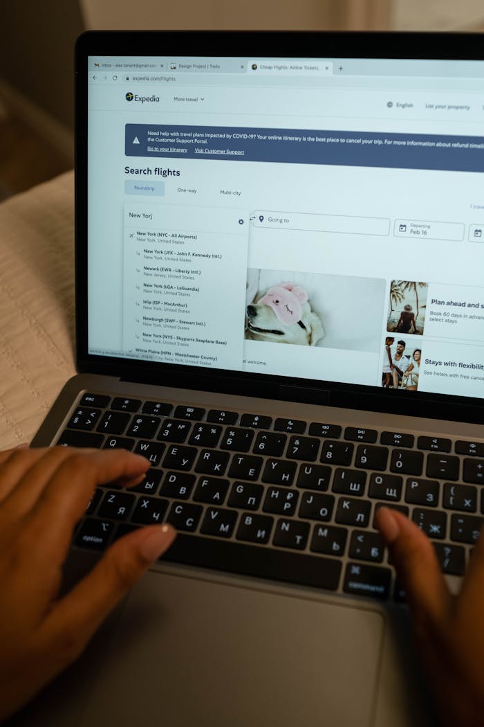 about-01 Person typing on laptop, searching flight details indoors, focusing on travel planning and booking.
